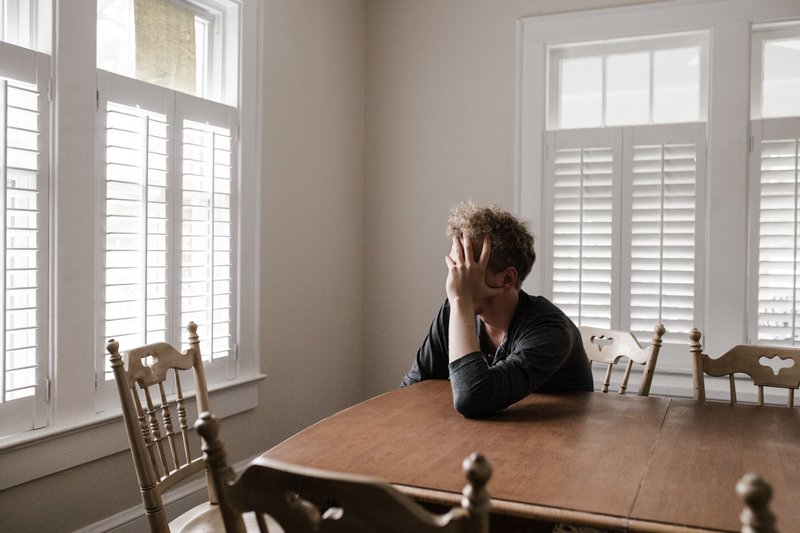 man sitting alone at a table, staring at the window, emotions