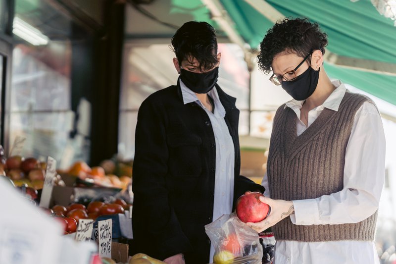 two women at a market wearing masks