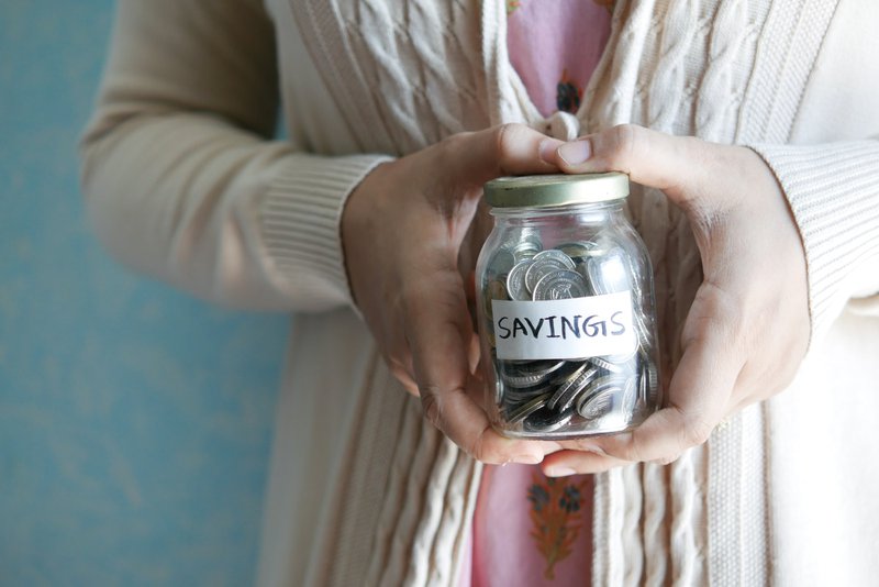 person holding a jar with coins labelled savings