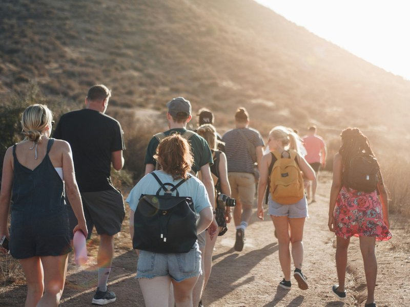 people walking on dirt road near mountain during daytime